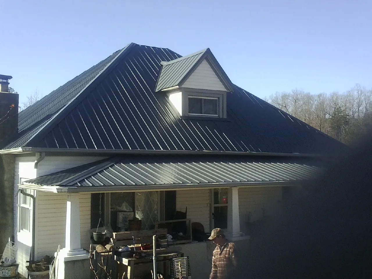 Dark blue standing seam metal roof with a dormer above a front porch in Harbeson