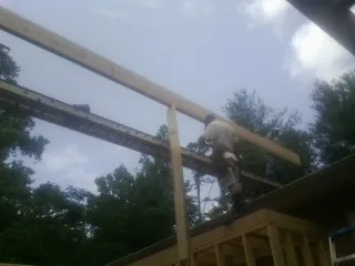Carpenter setting a ridge beam over a new addition frame — Ice Dam Removal by Roofing Brothers in Harbeson