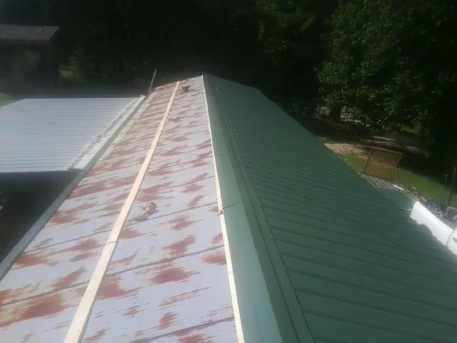 Old rusted panels beside newly installed green metal roofing — Wind Damage Roof Repair by Roofing Brothers in Harbeson
