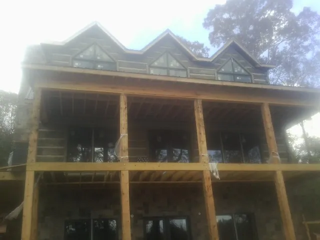 Dormers and porch framing on a large log home under construction — Roof Coating work by our crew in Harbeson