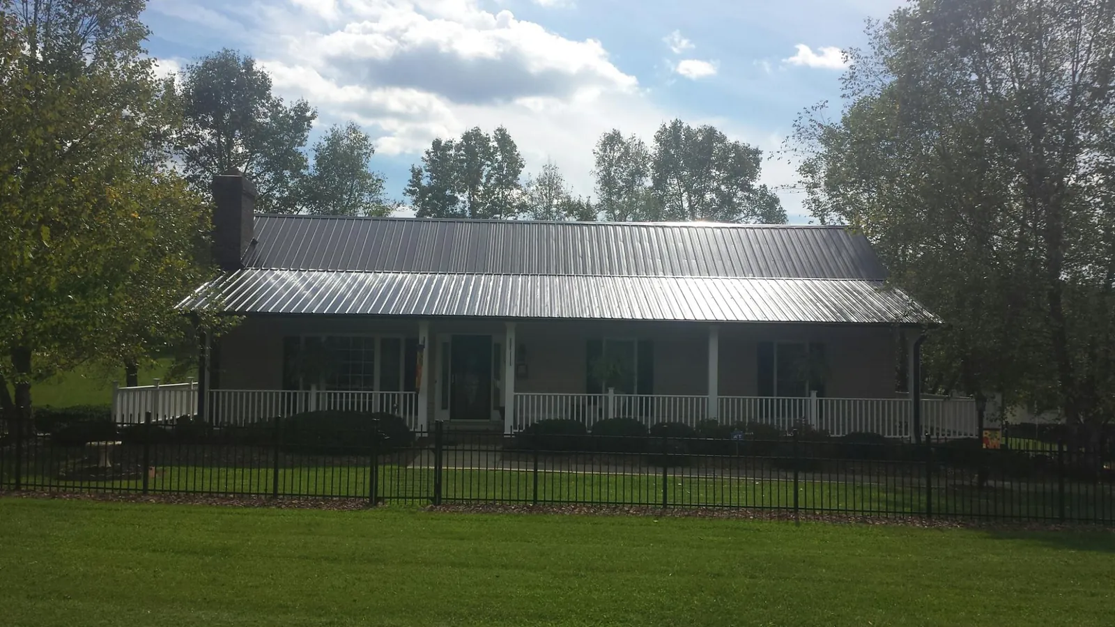 Gray metal roof on a brick ranch with a full width front porch — Gutter Guard Installation work by our crew in Harbeson