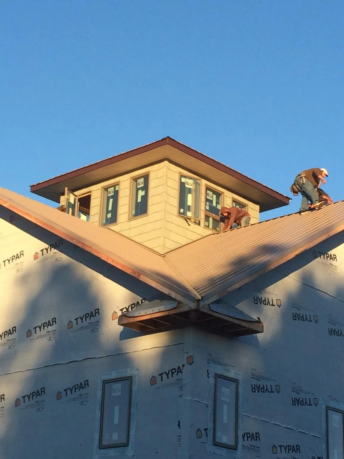Roofers working around a rooftop cupola on a new metal roof at sunset — Roof Waterproofing in Harbeson by Roofing Brothers